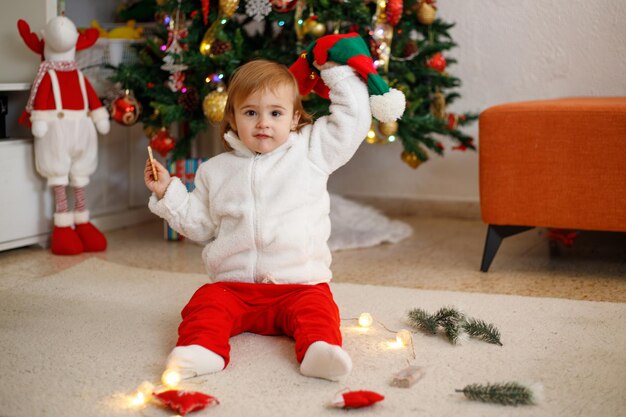 Adorable little girl having fun on a soft carpet in front of a Christmas tree