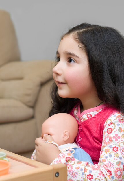 Adorable little girl holding a doll