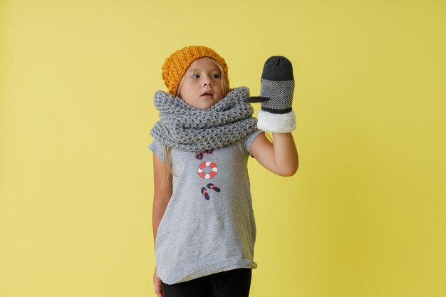 Фото Очаровательная маленькая девочка в вязаной шапке, стоя в студии