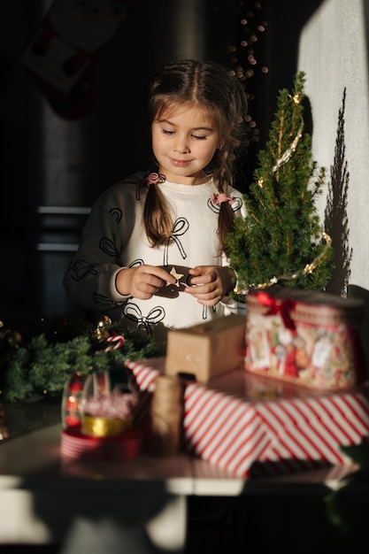 Adorable little girl making christmas wreath using fresh pine branches and festive decorations