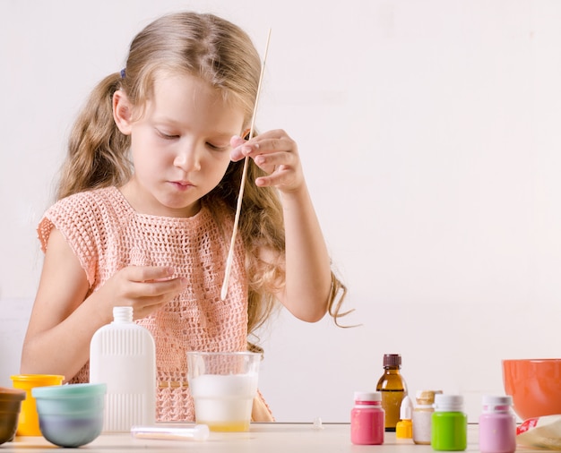 Adorable little girl making slime toy, meshes ingredients for  popular self made toy.