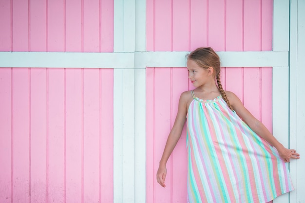 Adorable little girl outdoors near traditional caribbean colorful pink house