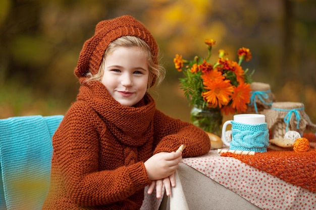 秋の公園でのピクニックのかわいい女の子。秋の庭でお茶会を持つかわいい女の子。