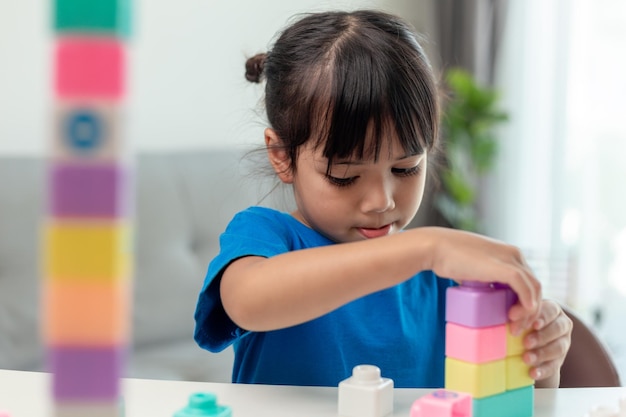 Очаровательная маленькая девочка, играющая в игрушечные блоки в светлой комнате