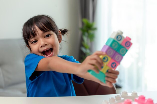 Adorable little girl playing toy blocks in a bright room