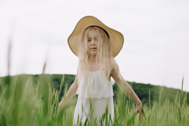 Adorable little girl playing in the wheat field on a warm summer day