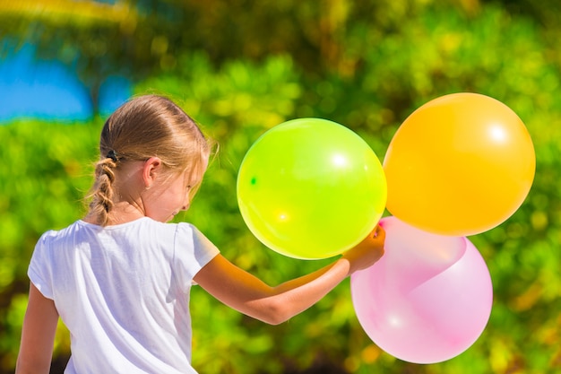 Adorable little girl playing with balloons at the beach