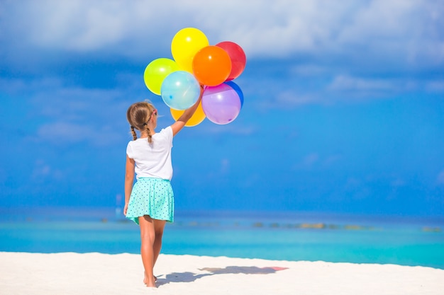 Adorable little girl playing with balloons at the beach