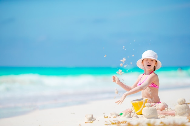 Adorable little girl playing with beach toys during tropical vacation