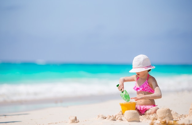 Adorable little girl playing with beach toys on the white beach