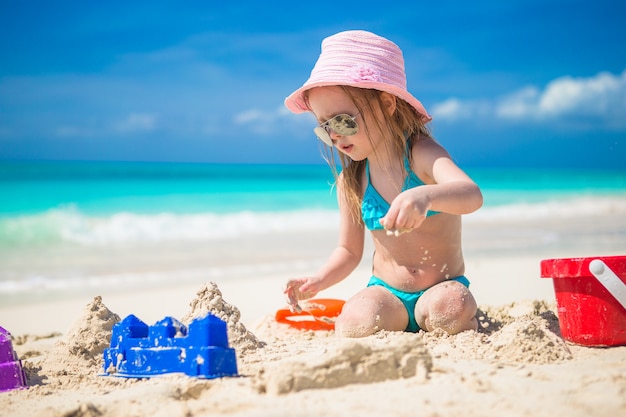 Adorable little girl playing with toys on beach vacation