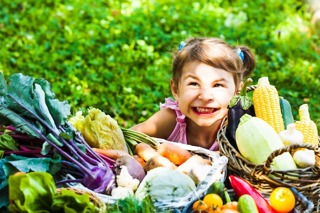 Adorable little girl plays with a variety of vegetables on the lawn