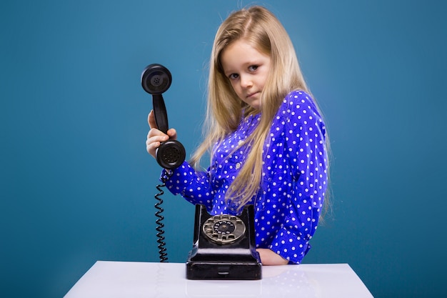 Adorable little girl in purple dress holds phone handset