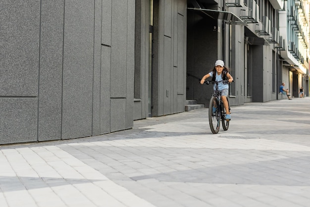 Adorable little girl riding a bike in a city