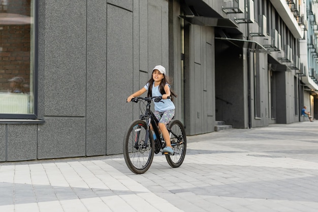 Adorable little girl riding a bike in a city