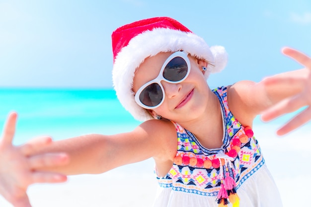 Adorable little girl in Santa hat during Christmas beach vacation