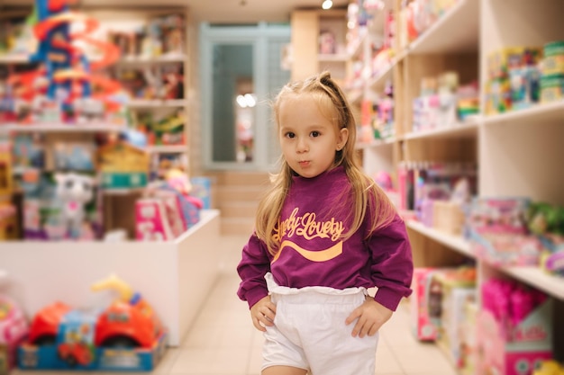 Adorable little girl shopping for toys cute female in toy store happy young girl selecting toy