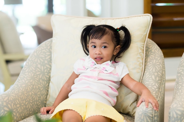 Adorable little girl sitting on sofa