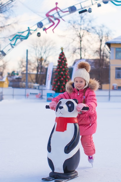 Photo adorable little girl skating on the ice-rink