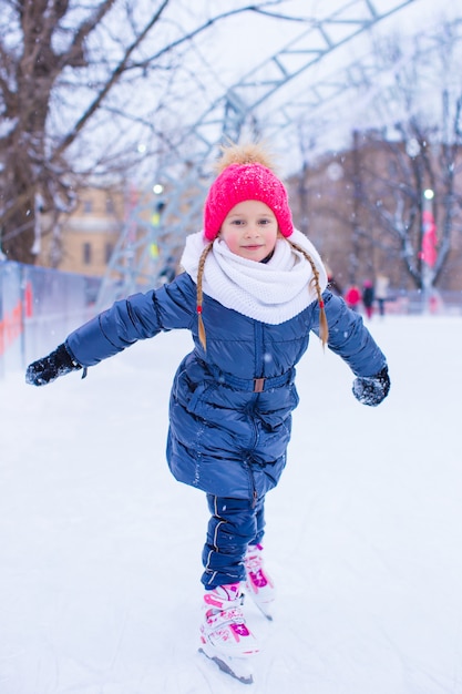 Adorable little girl skating on the ice-rink