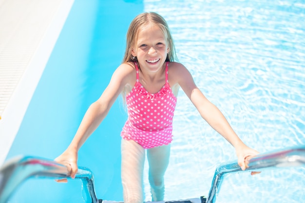 Adorable little girl swimming at outdoor swimming pool