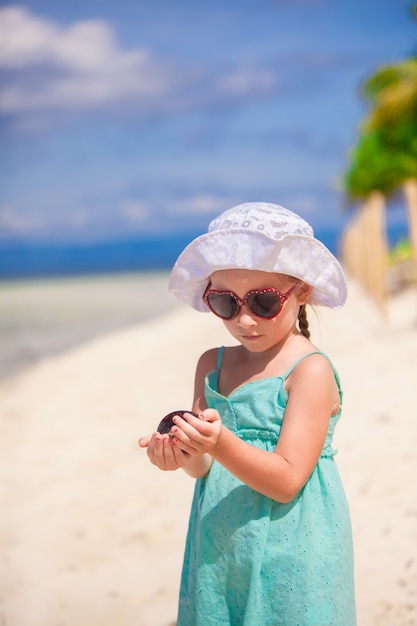 Adorable little girl on tropical beach vacation at Phillipines with shell in hand