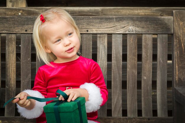 Adorable Little Girl Unwrapping Her Gift on a Bench