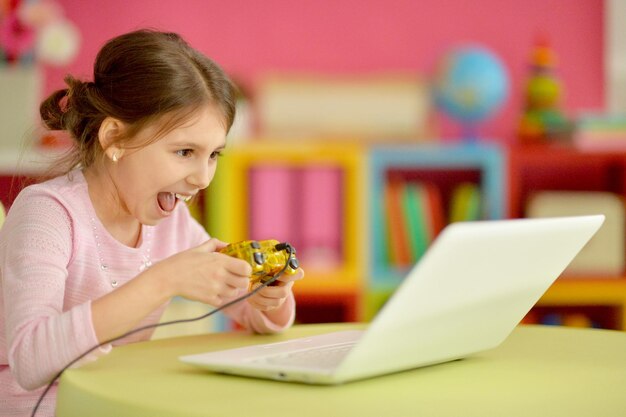 Adorable little girl using modern laptop and playing game