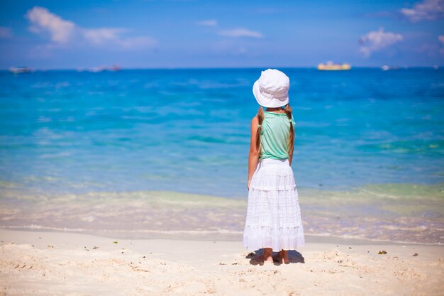 Bambina adorabile che cammina sulla spiaggia bianca tropicale