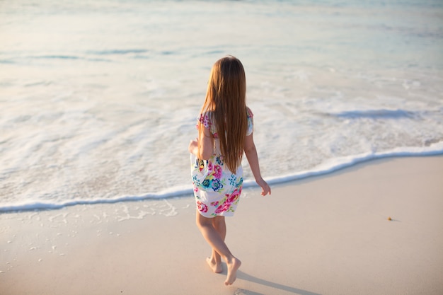 Bambina adorabile che cammina alla spiaggia tropicale bianca