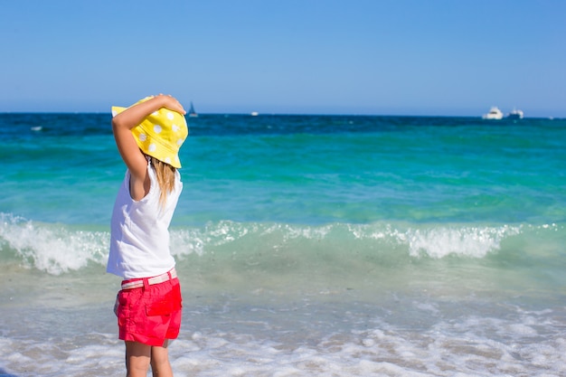 Adorable little girl at white beach during tropical vacation