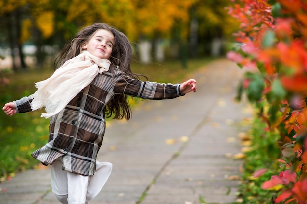 adorable little girl with autumn leaves in the beauty park