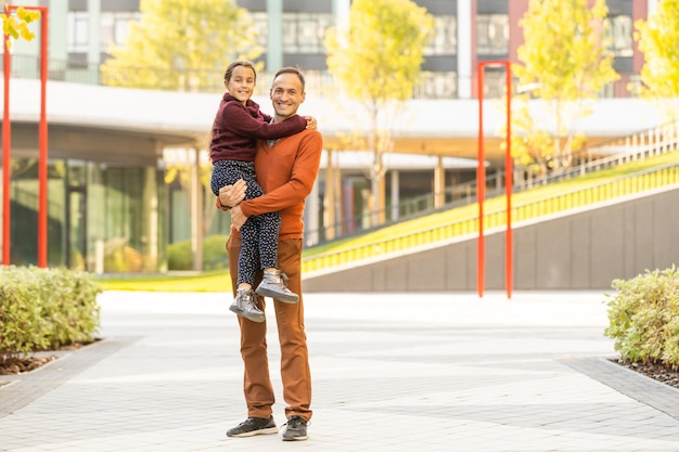 Foto bambina adorabile con padre felice che cammina nel parco d'autunno in una giornata di sole.