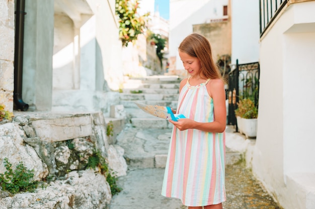 Adorable little girl with map of european city outdoors