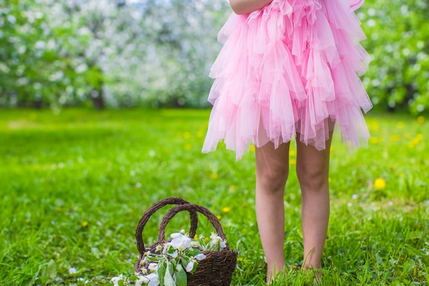 Adorable little girl with straw basket in blossoming apple garden