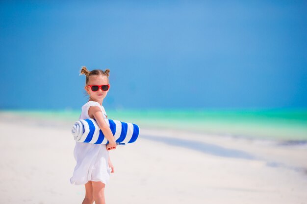 Adorable little girl with towels at tropical vacation