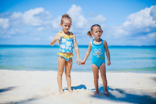 Adorabili bambine sulla spiaggia durante le vacanze estive con oceano turchese e sabbia bianca