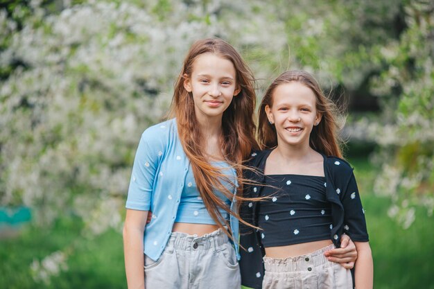 Photo adorable little girls in blooming apple tree garden on spring day