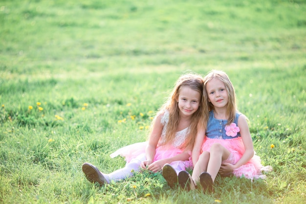 Adorable little girls on spring day outdoors sitting on the grass