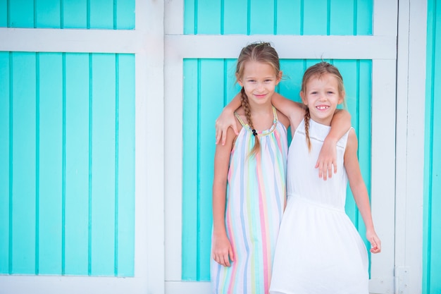 Adorable little girls on summer vacation background traditional colorful caribbean house