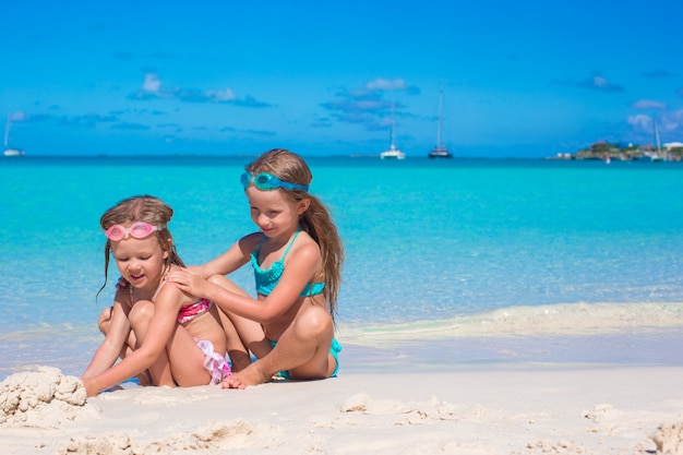 Adorable little girls in swimsuit and glasses for swimming at tropical beach