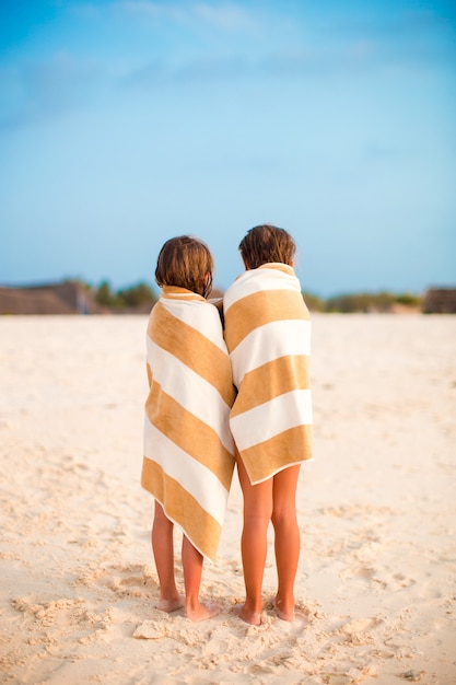 Очаровательные маленькие девочки, завернутые в полотенце на тропическом пляже