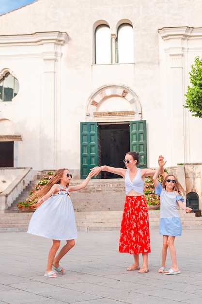 Adorable little girls and young mother have fun in italian old village