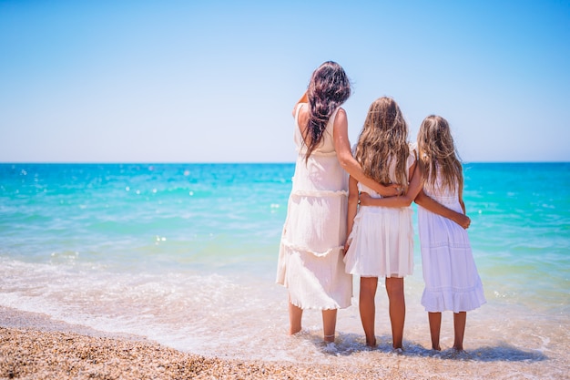 Adorable little girls and young mother on tropical white beach