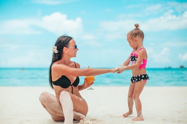 Bambine adorabili e giovane madre sulla spiaggia bianca tropicale