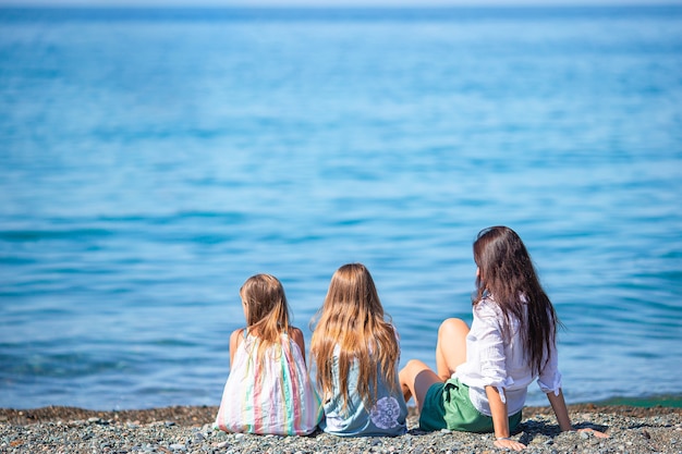 Adorable little girls and young mother on tropical white beach