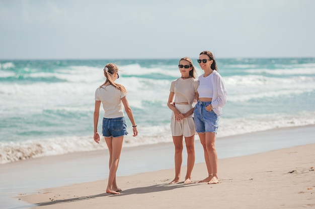 Adorable little girls and young mother on tropical white beach