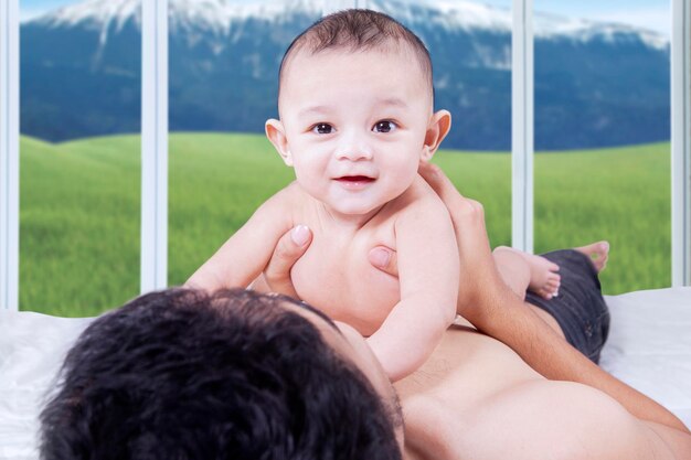 Adorable male baby lying on father stomach