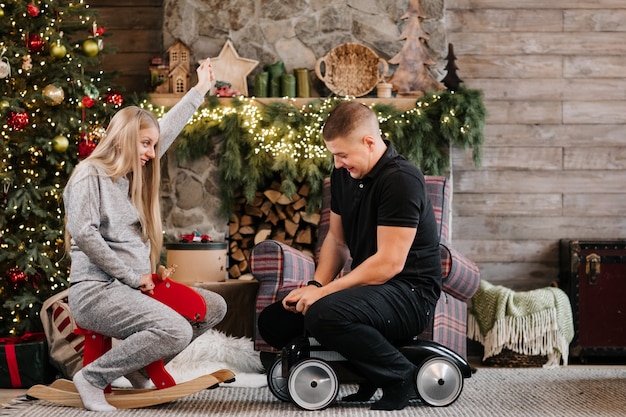 Foto adorabile coppia incinta matrimonio vicino all'albero di natale e camino a casa