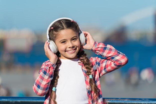 愛らしい音楽愛好家小さな子供は音楽を聴くのを楽しんでいますステレオヘッドホンをつけている小さな女の子ワイヤレスヘッドセットを持っている小さな子供レジャーや音楽教育のための技術を使っている小さな子供